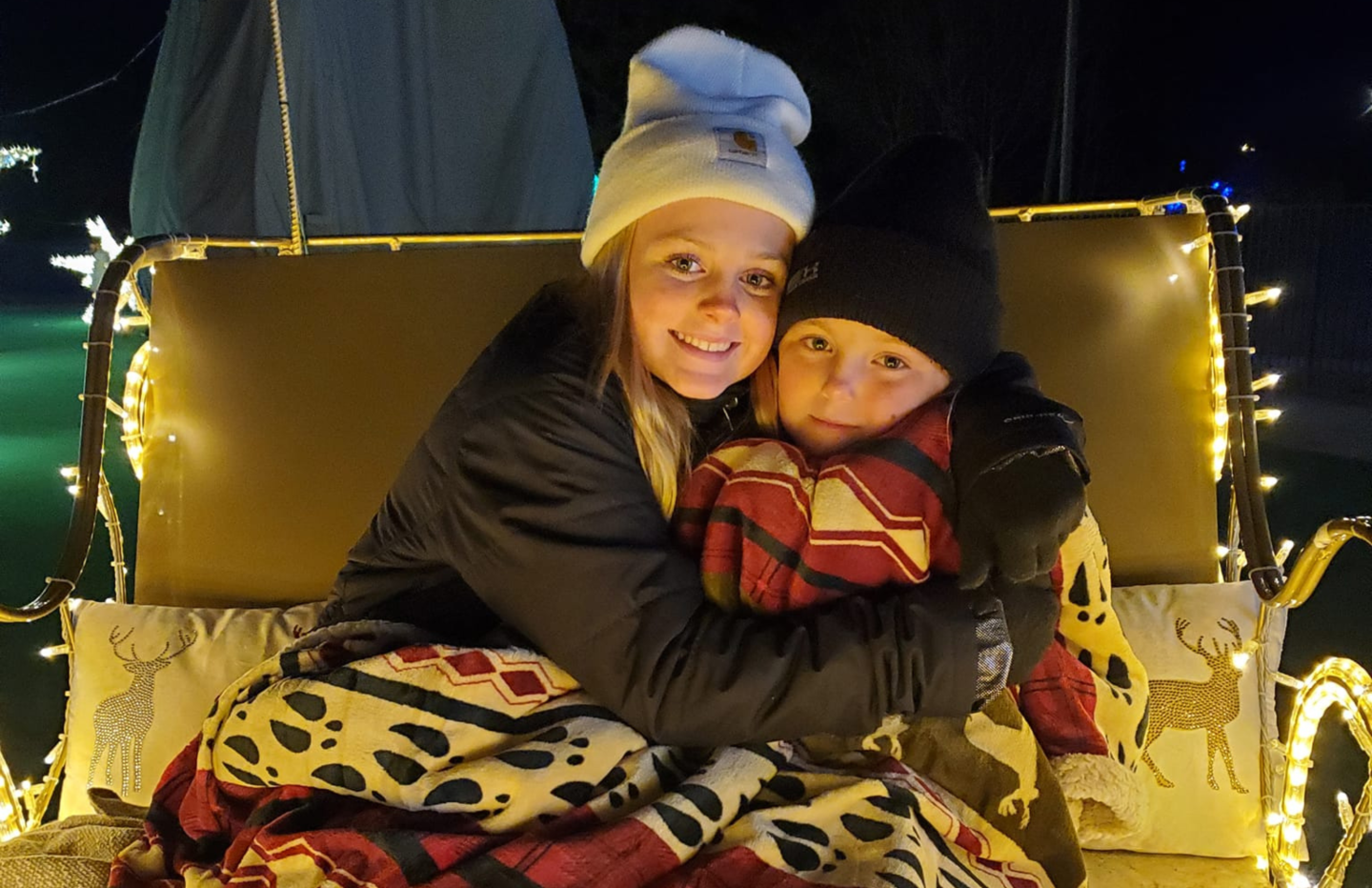 two girls under a blanket in a lighted sled Kid Night buy one get one free night at Ice and Lights