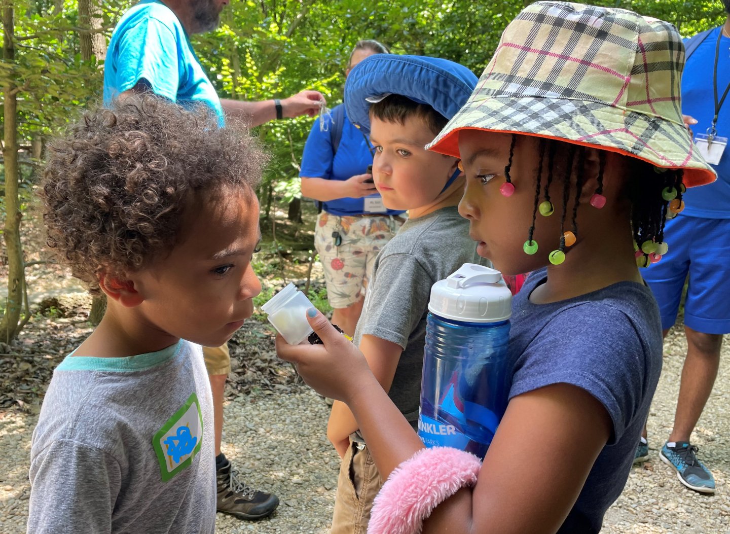 A girl and boy on field trip at Winkler Botanical Preserve  The boy is sniffing a container