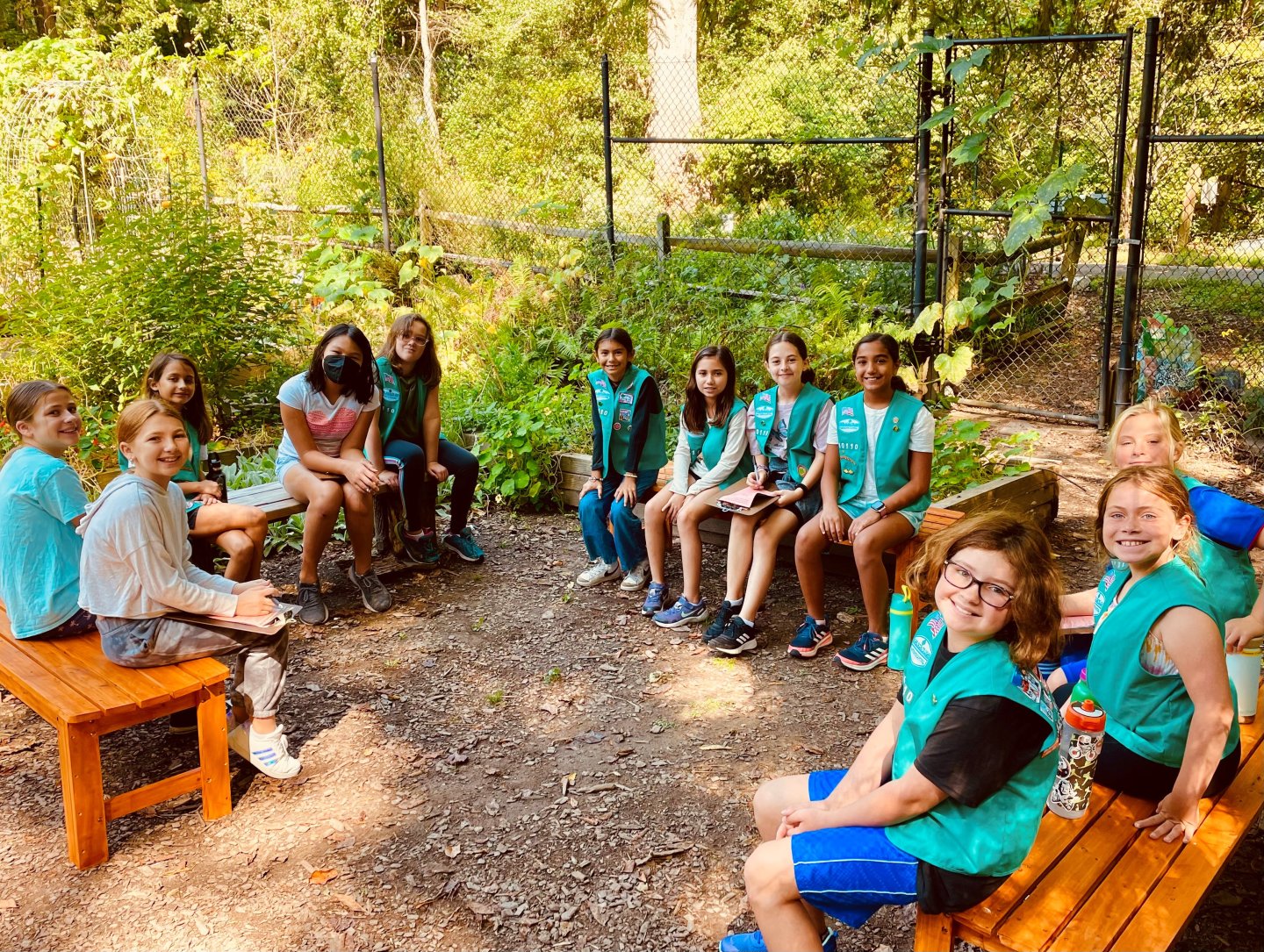 Group of Girl Scouts sitting on benches in a garden