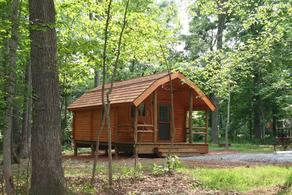 Bull Run Regional Park rustic cabin surrounded by trees with green leaves.