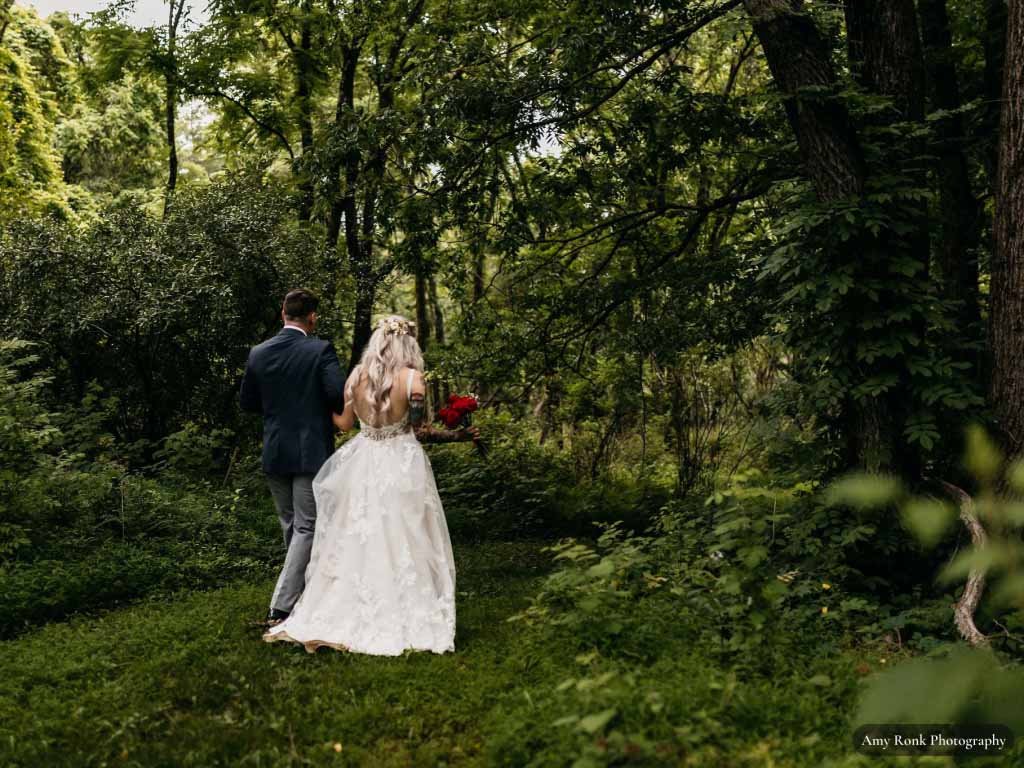 Bride and groom walking into a lush green garden