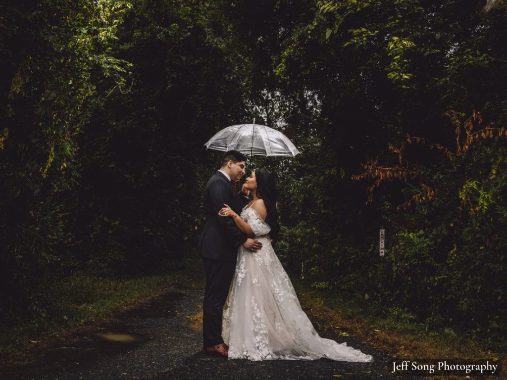 Bride and groom under umbrellas in forest
