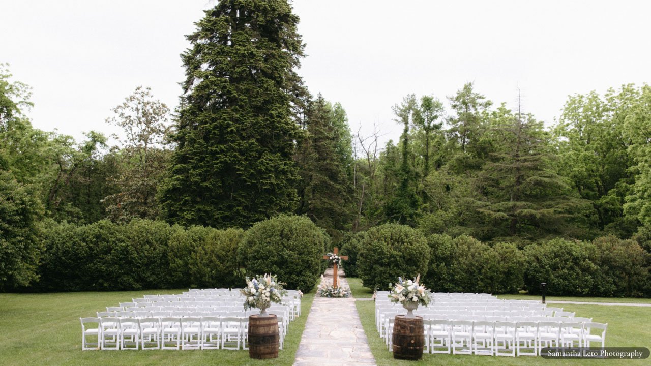 Gardens set up for wedding ceremony with white chairs.
