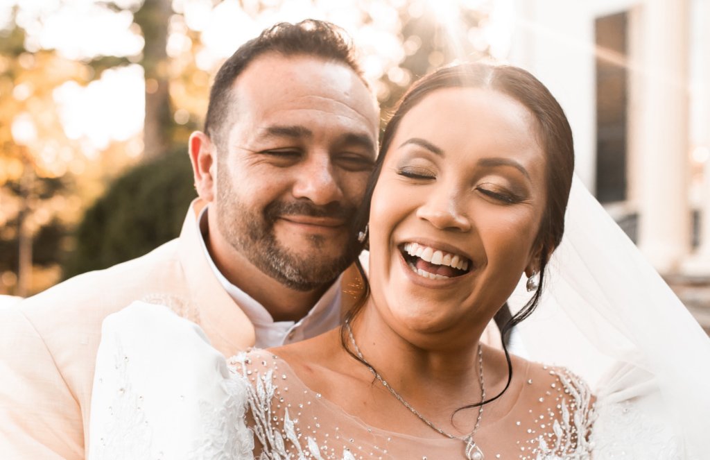 Rust Manor House bride and groom smiling with sun in background