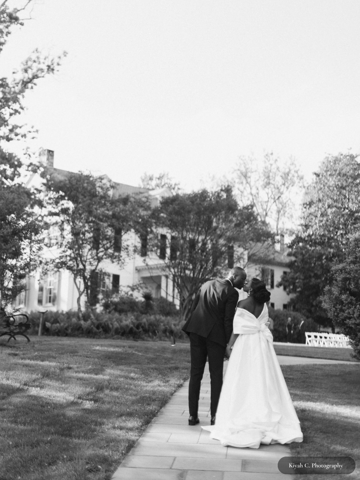 Black and white photo of bride and groom kissing in front of Rust Manor House