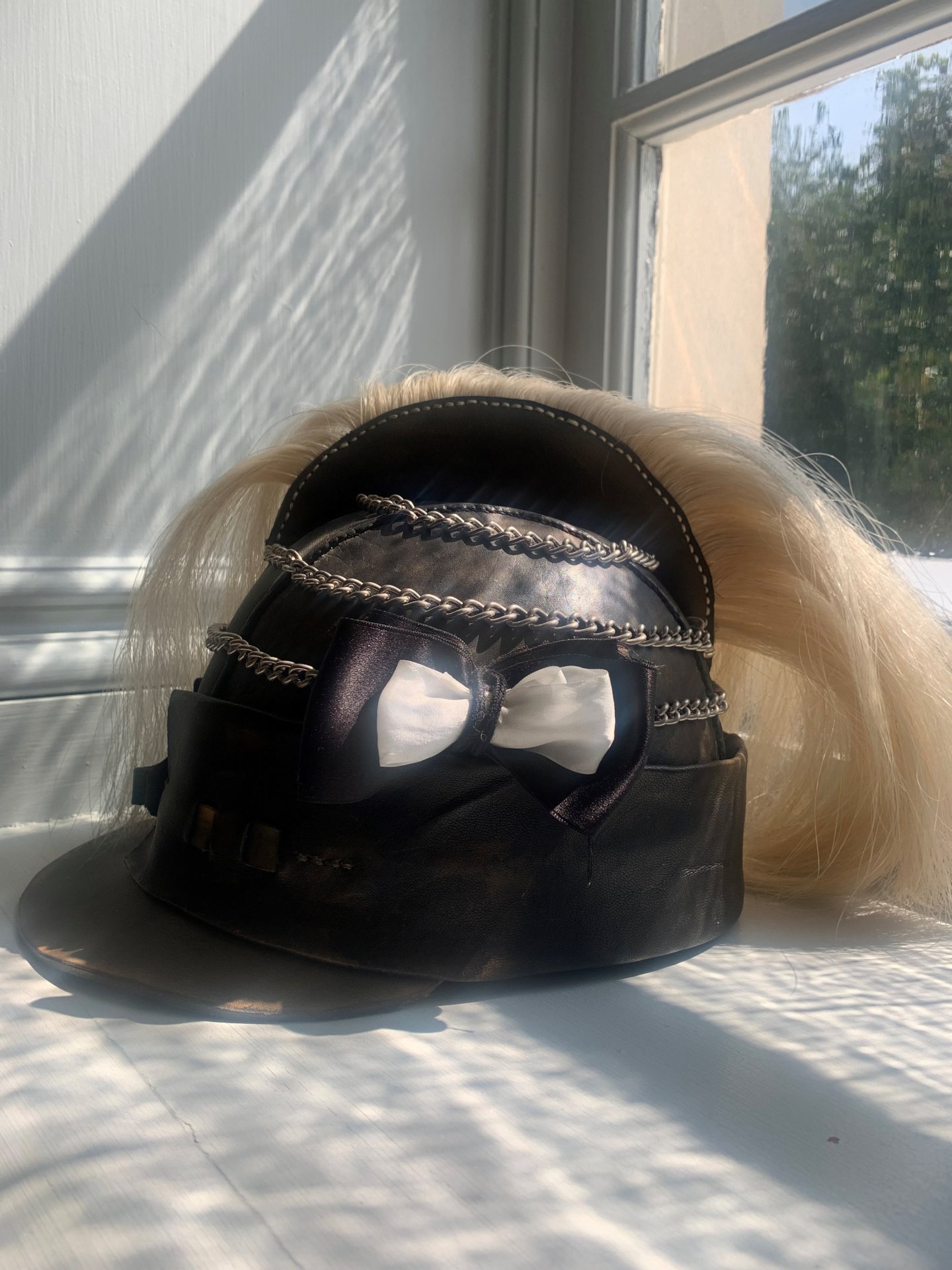 Black helmet with white hair along the crest. A black and white roset on the side of the helmet