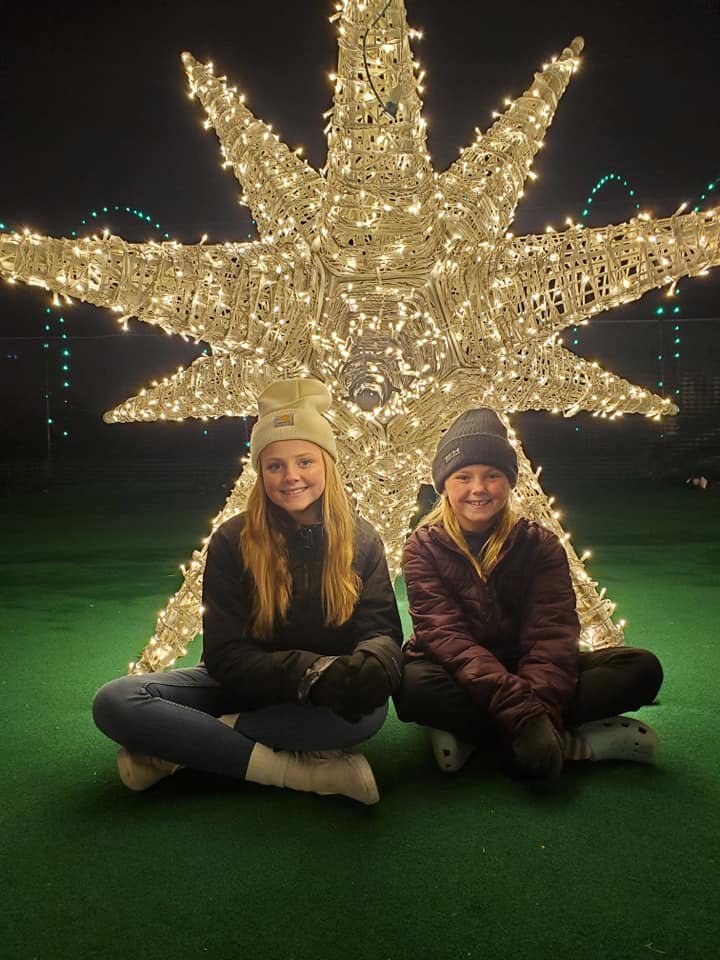 Two girls sitting in front of a giant lit up star