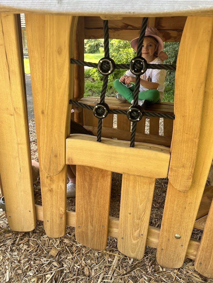 A young girl sitting in a woden playhouse at Meadowlark Botanical Gardens