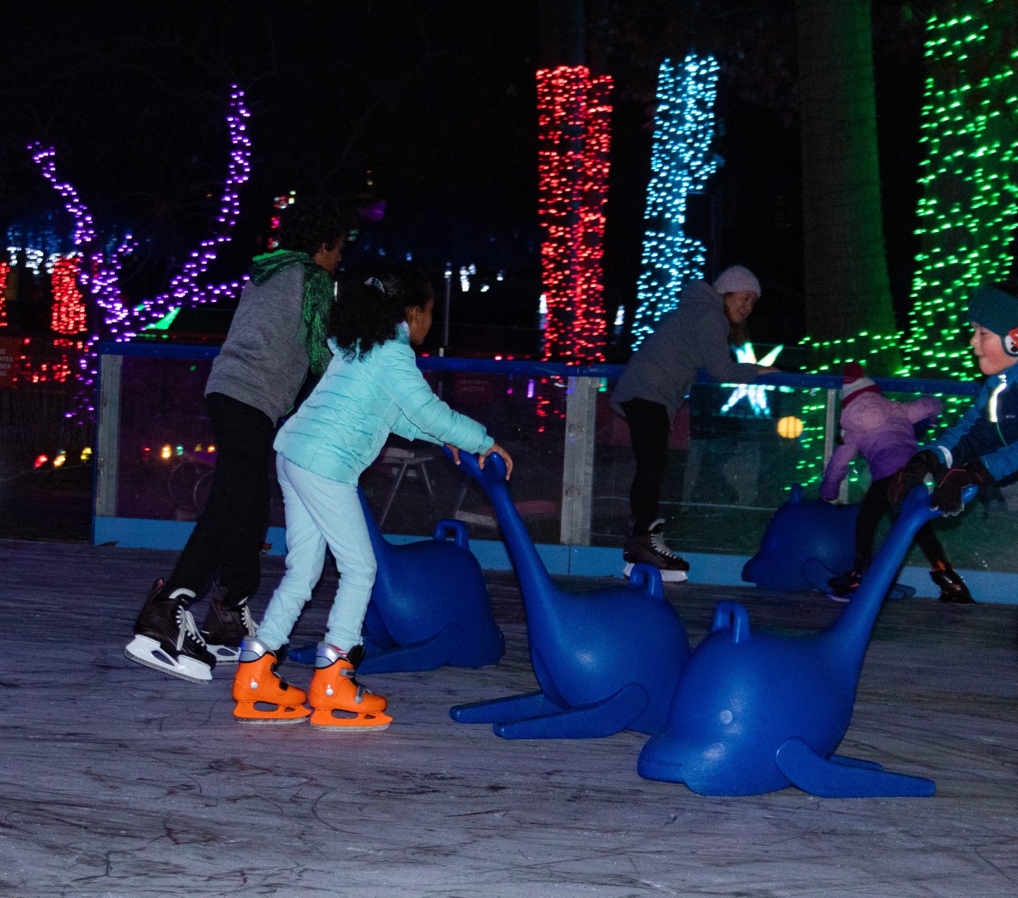 Kids ice skating with light displays in background