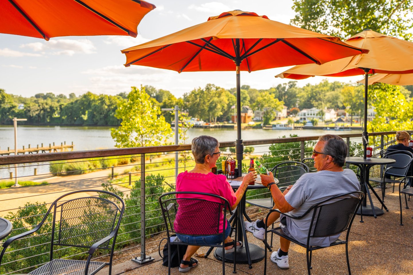 Two people cheering beers during happy hour on the Brickmakers Cafe patio