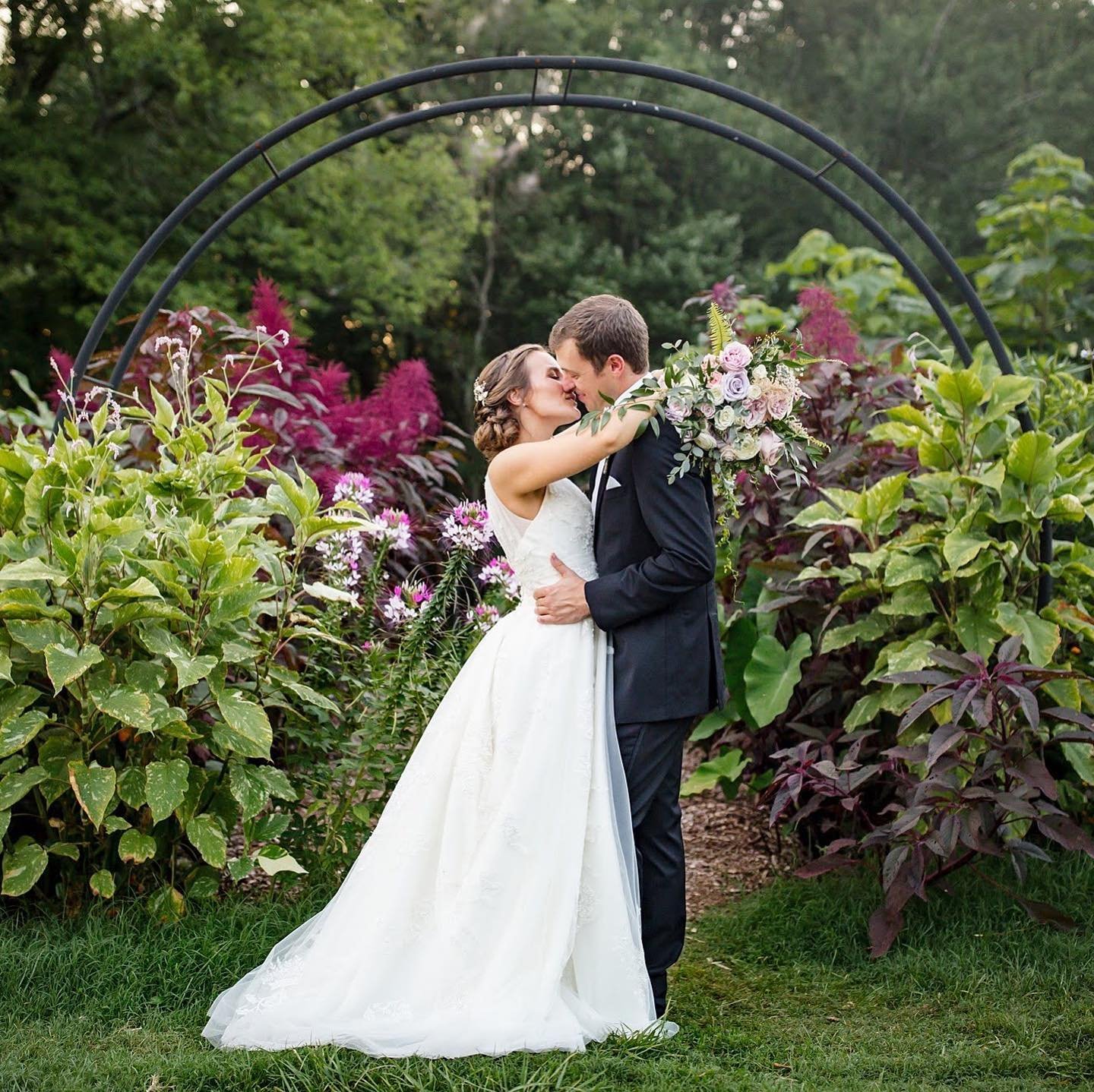 Newlyweds kissing under alter in gardens