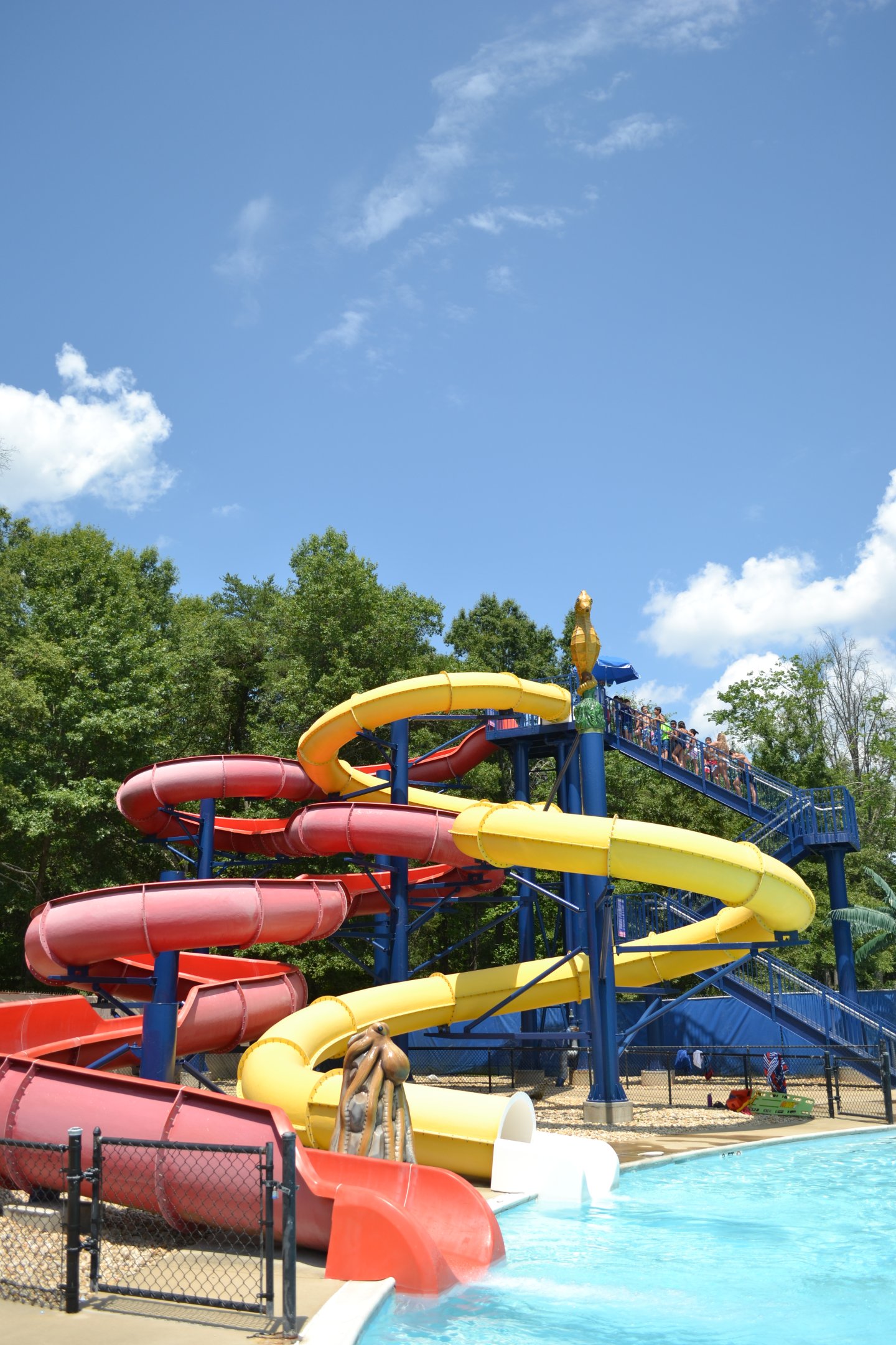 Colorful water slides spiraling into a pool under a clear blue sky.