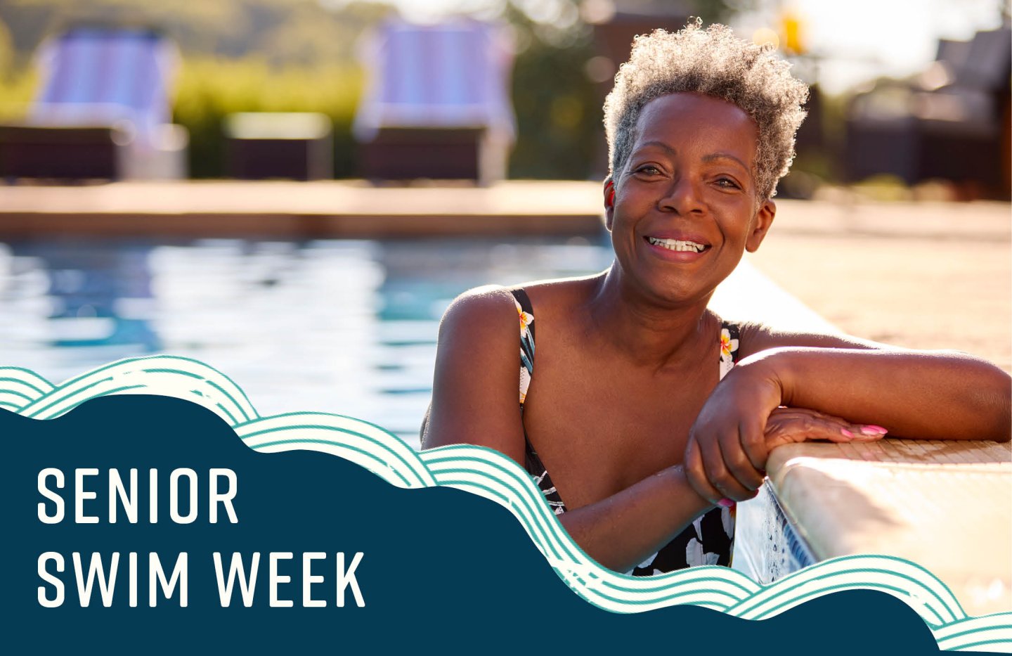 Woman smiling in a pool, sunny day, lounge chairs in background.