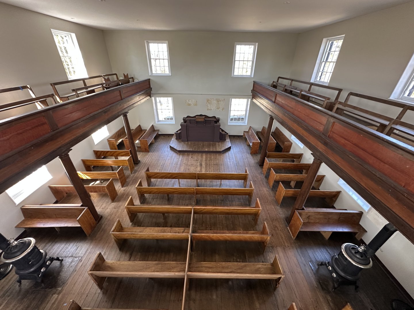 Symmetrical church interior with wooden pews and a high ceiling.