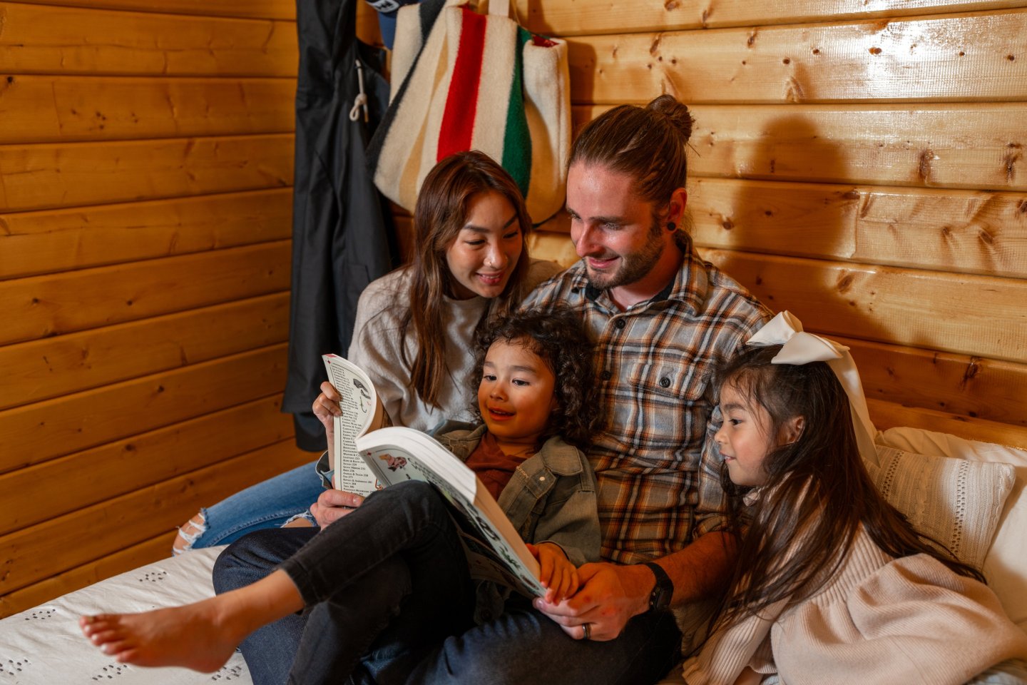 Family reading a book together in a cozy rustic cabin.