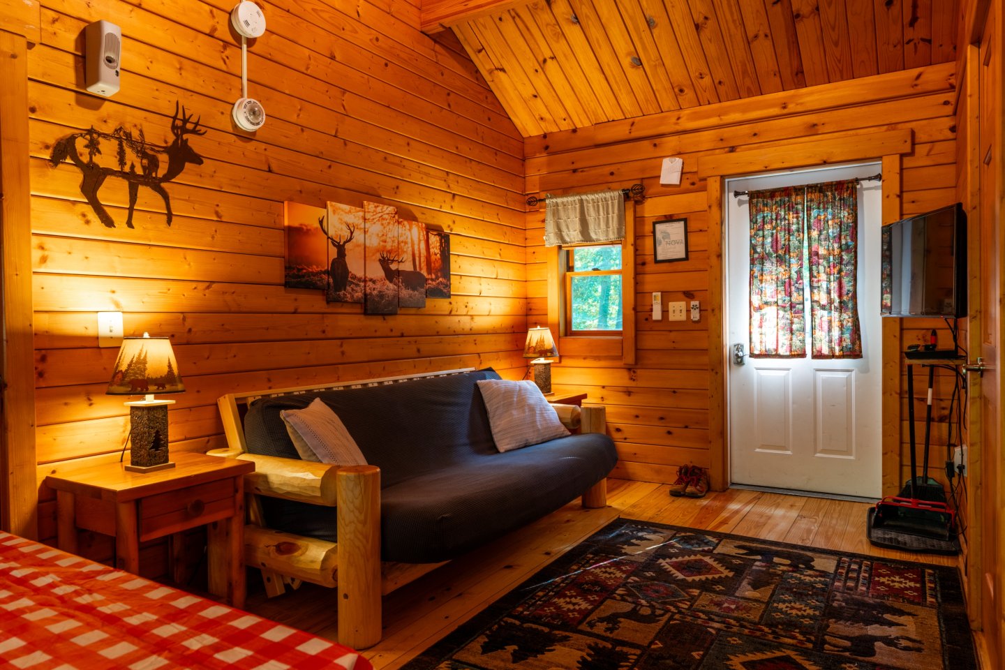 Cozy wooden cabin interior with a couch, lamp, and colorful curtains.