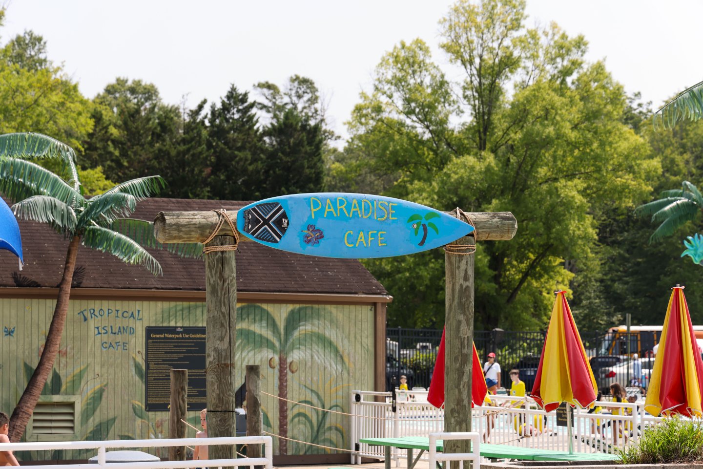 Paradise Café with colorful umbrellas and palm trees, set against a lush green backdrop.