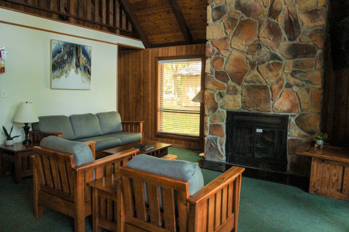 Cozy living room with stone fireplace, wooden furniture, and large window.