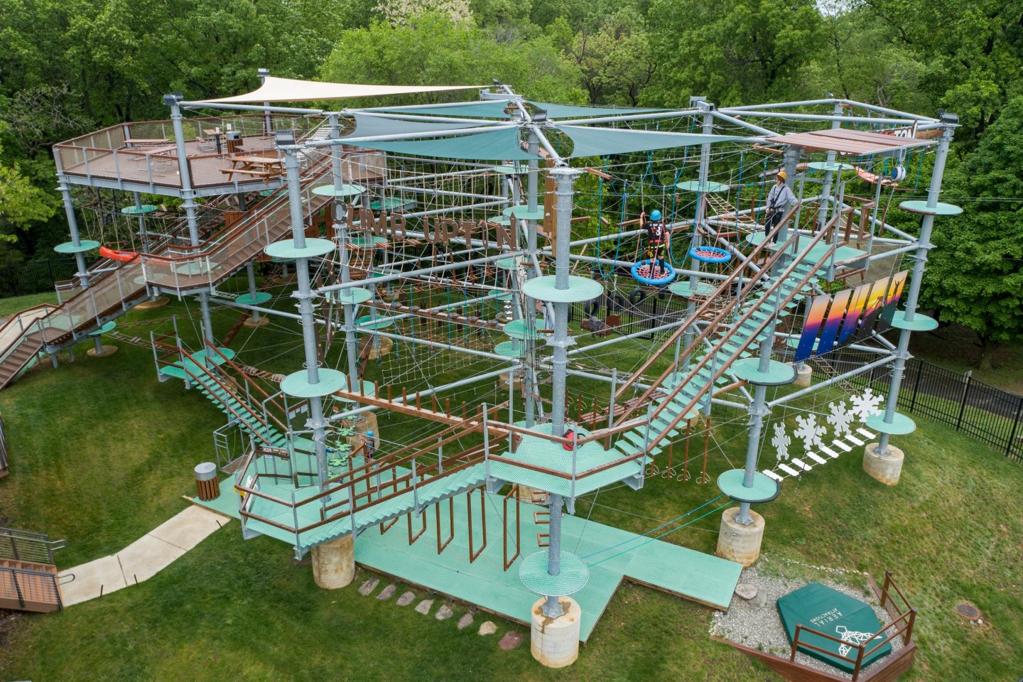 Rope course with platforms and bridges in a green park setting.