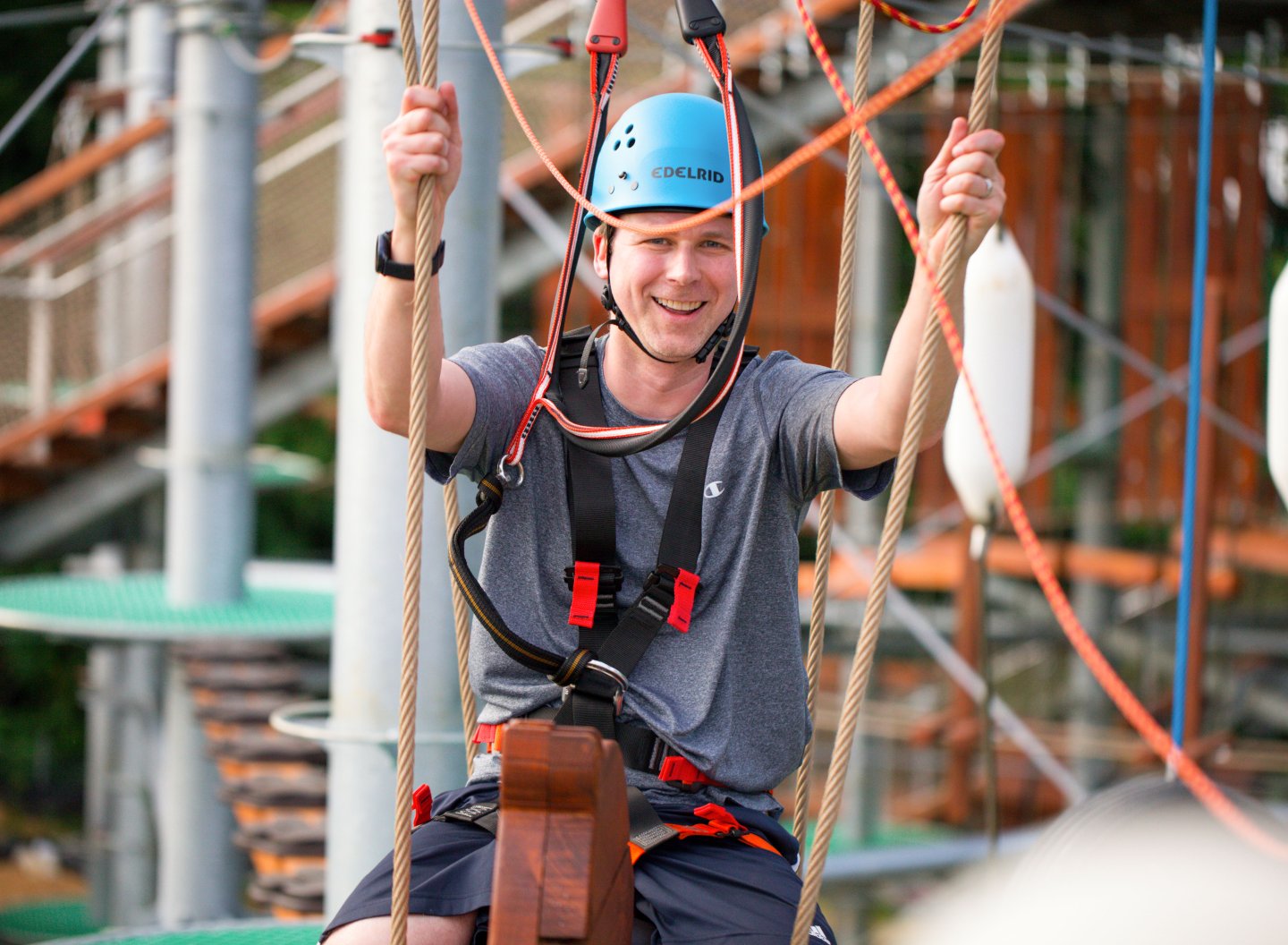 Man in helmet enjoying a ropes course outdoors.