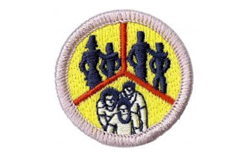 Circular fabric badge with silhouettes and figures on a yellow background