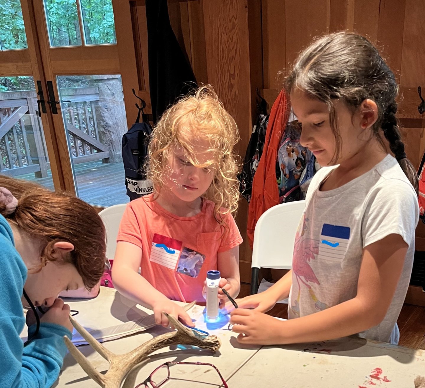 Children crafting at a table, indoors.