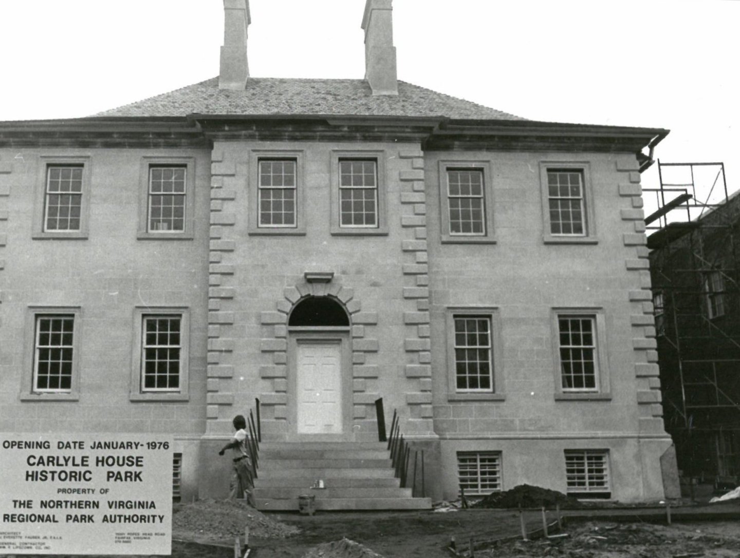 Historic building with two chimneys and symmetrical windows, under construction.