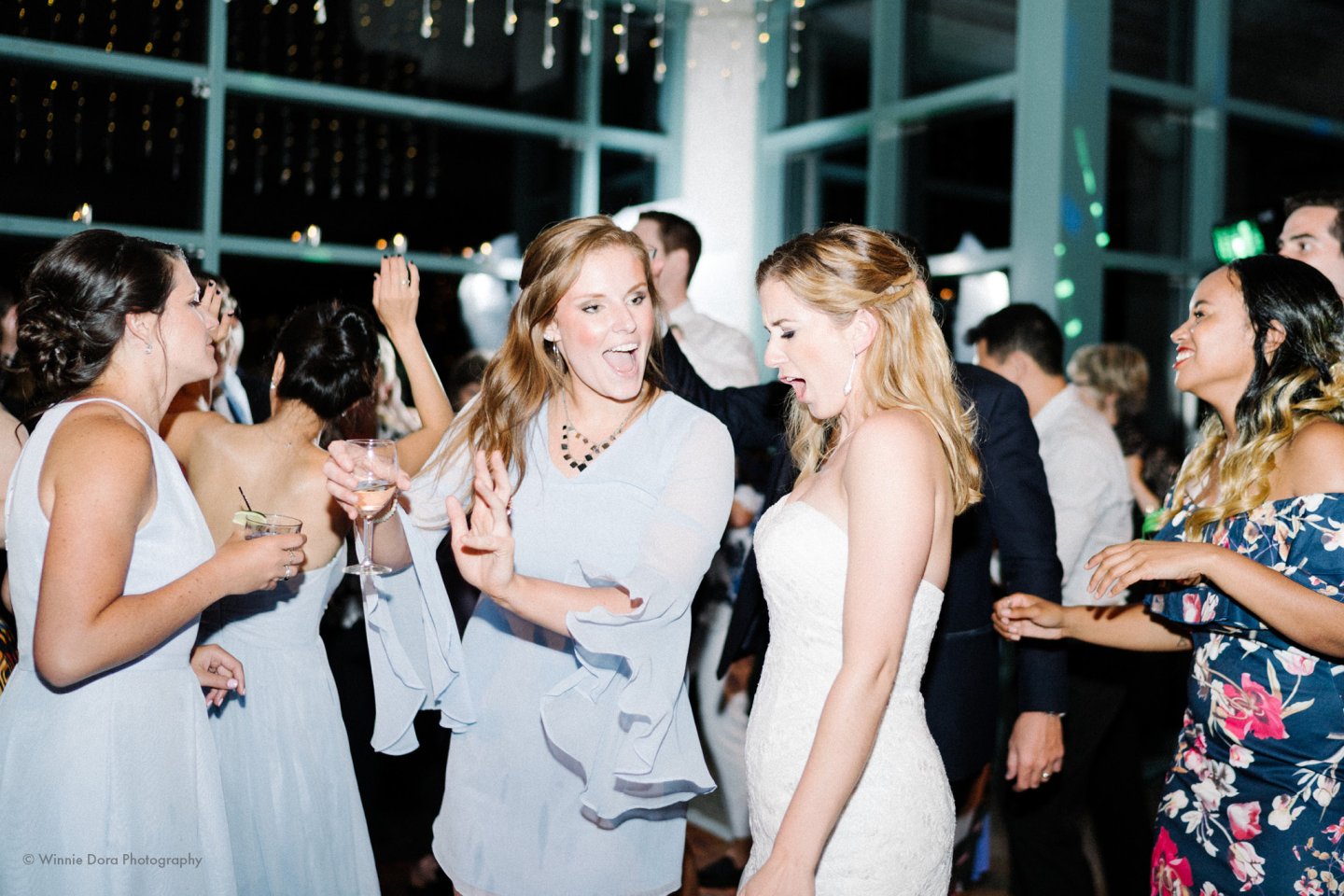 Guests dancing joyfully in a well-lit indoor wedding reception.