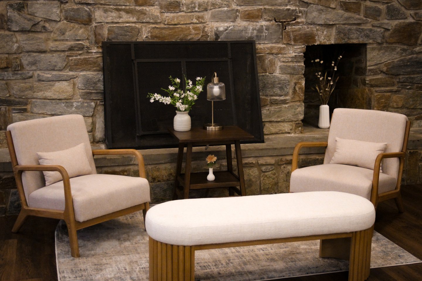 Cozy seating area with chairs, bench, and stone fireplace.