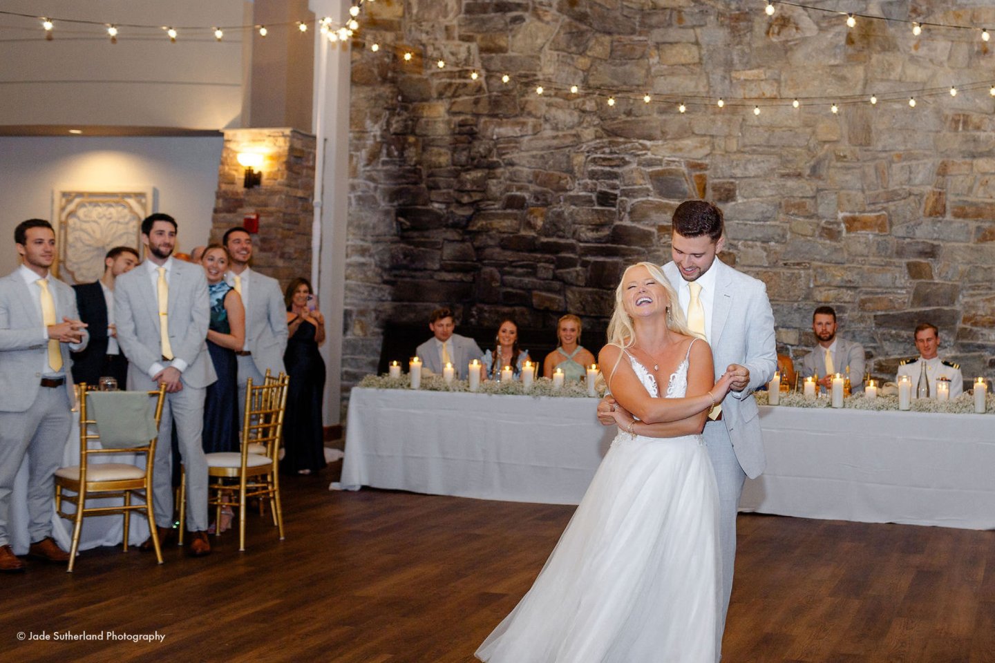 Bride and groom share a first dance in a warmly lit reception hall.