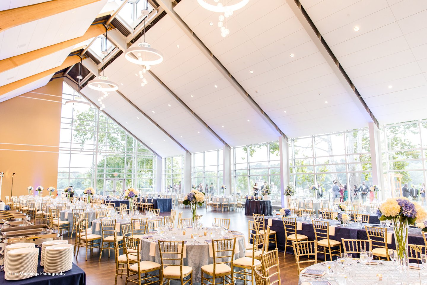 Elegant banquet hall with round tables, gold chairs, and large windows.
