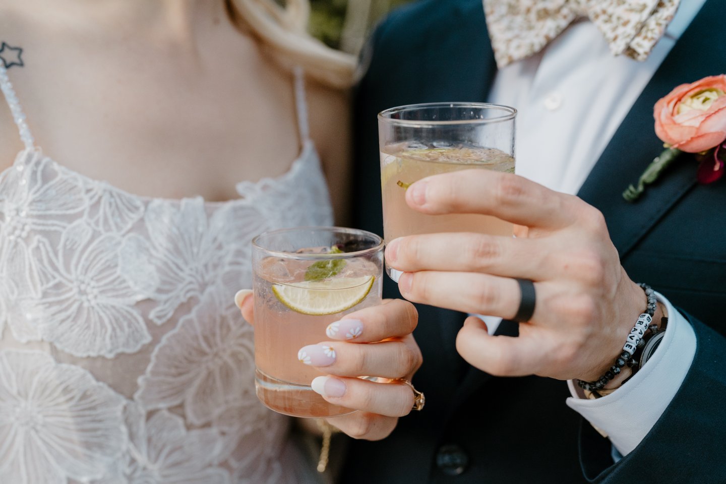 Bride and groom holding cocktails with lime garnish.