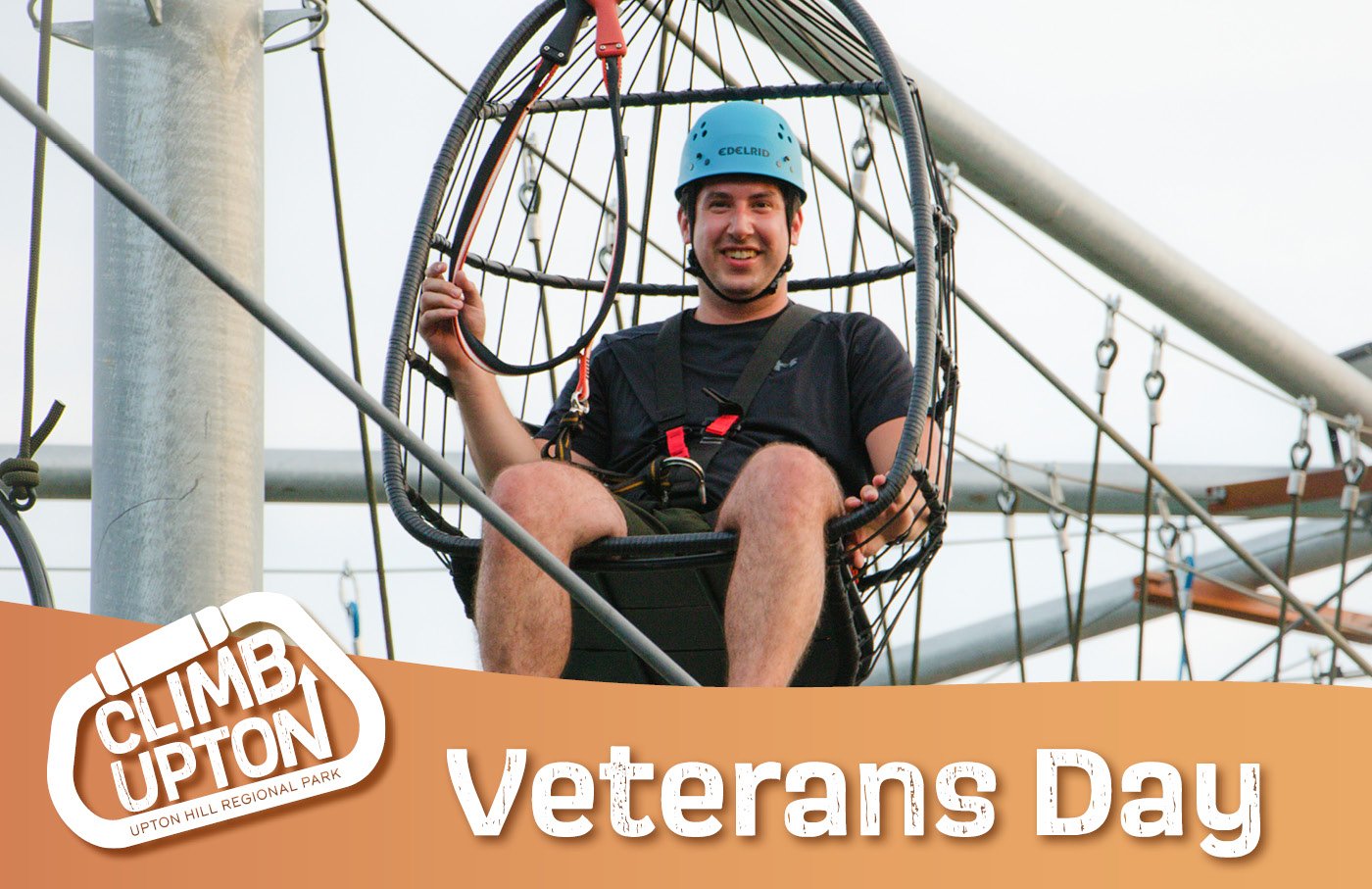 Man in a helmet on a climbing apparatus, smiling, with ropes and platforms.