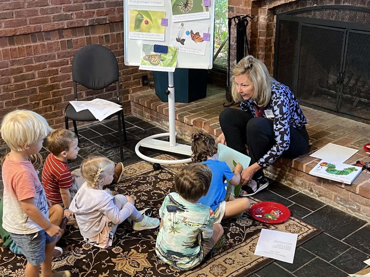 Woman reading to children seated on a rug in a cozy room.