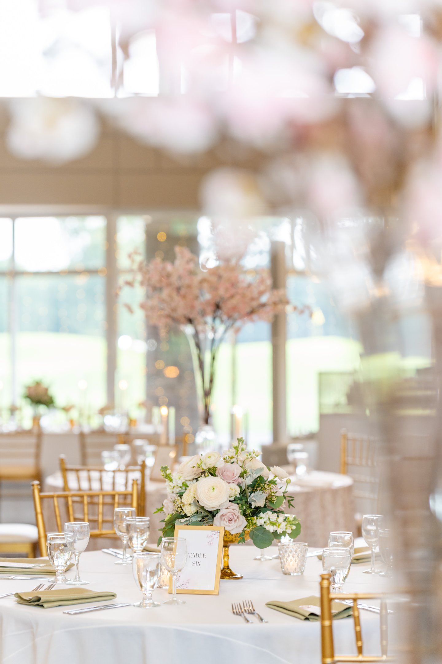 Elegant wedding table setting with floral centerpiece and gold chairs.