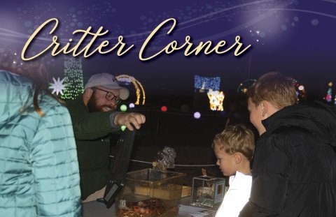 People interacting at an outdoor event under "Critter Corner" sign.
