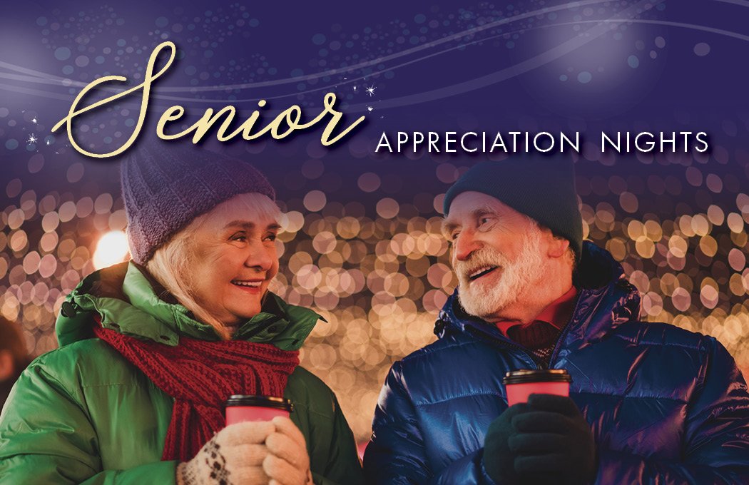Elderly couple smiling, holding hot drinks in a festive setting.