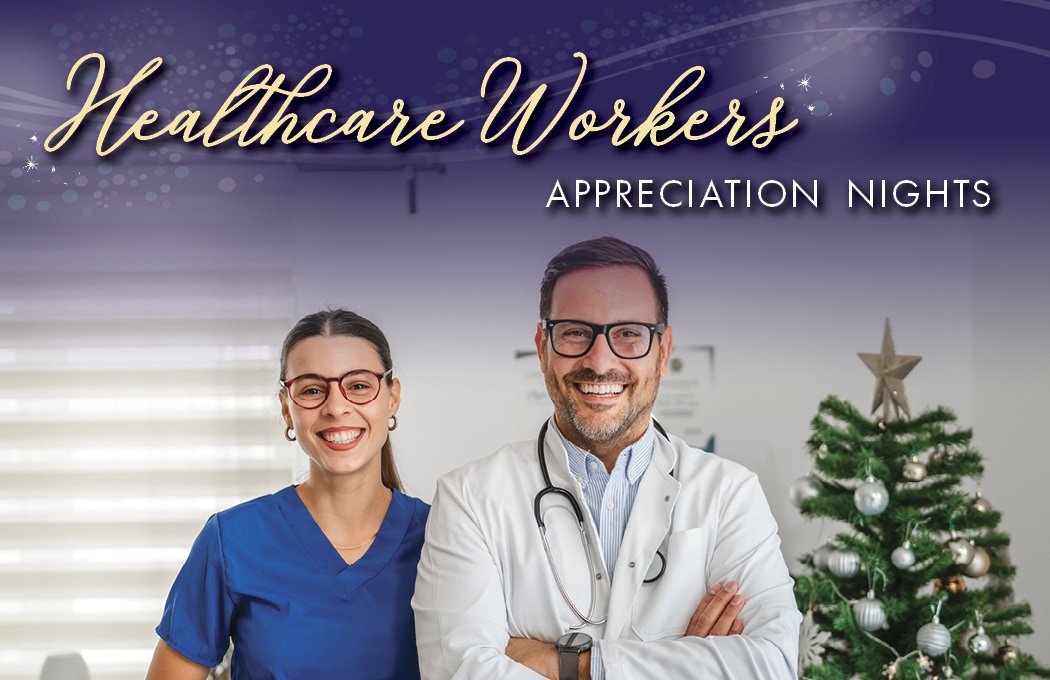 Smiling healthcare professionals stand by a Christmas tree.