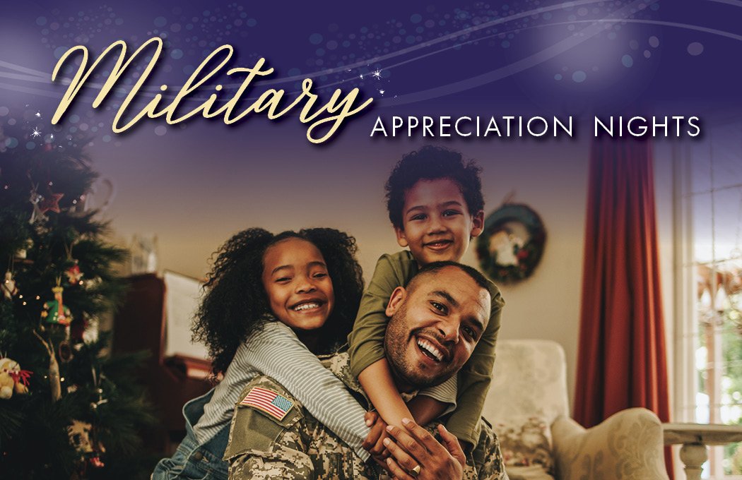 Father in military uniform smiling with two children by a Christmas tree.