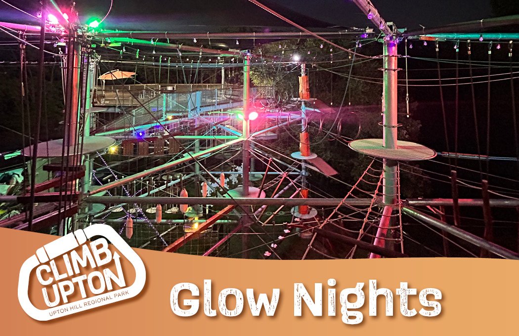 Rope course at night illuminated by colorful lights.