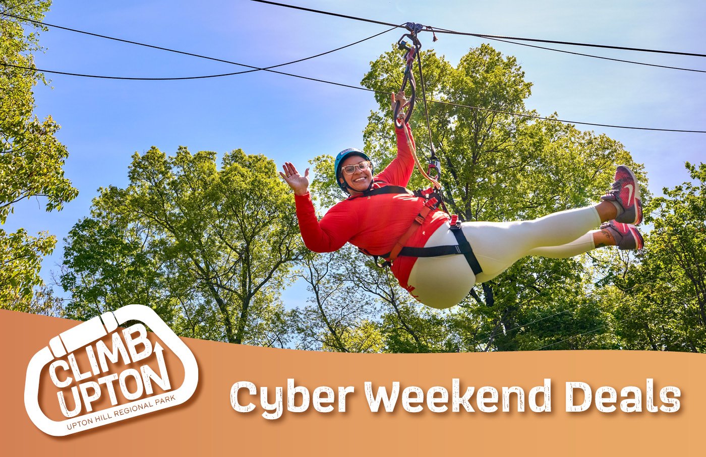 Person zip-lining through trees, smiling, with a lush green background.