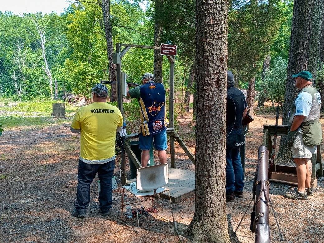 People shooting at a clay pigeon range in a wooded area.