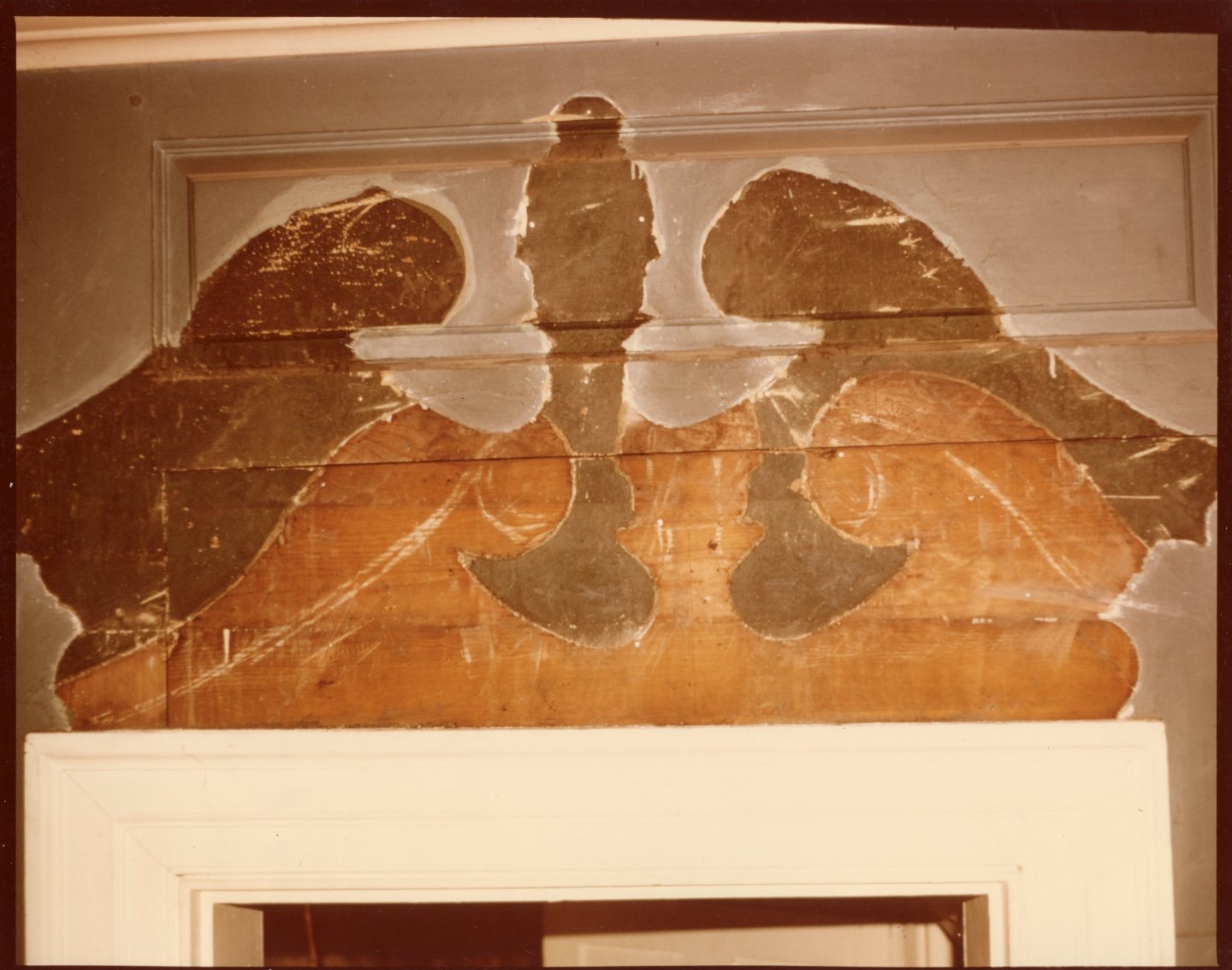 Aged mural above a doorway with peeling paint and abstract figures.