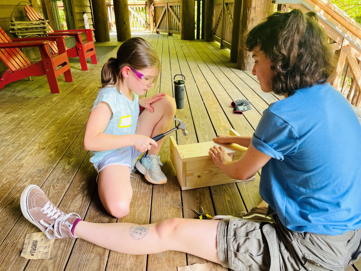 Girl and woman building a wooden box on a porch.