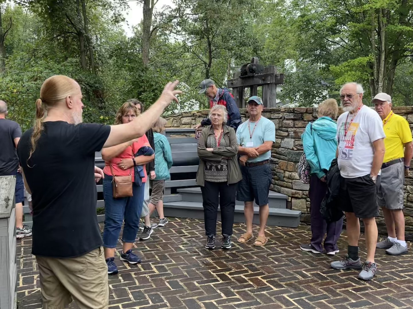 Tour guide gestures to a group of attentive people in an outdoor setting.