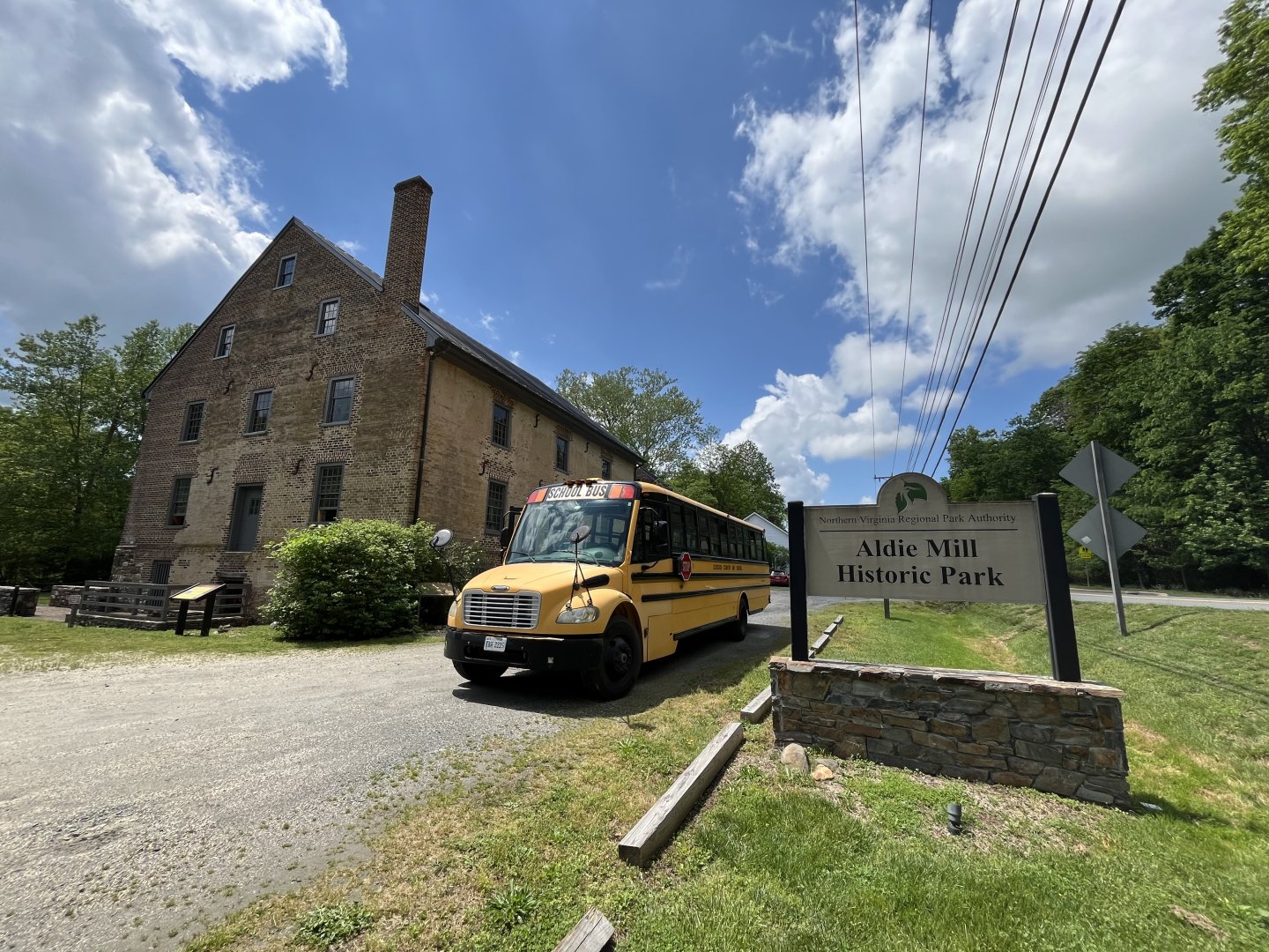 Yellow school bus in front of an old stone building under a blue sky.