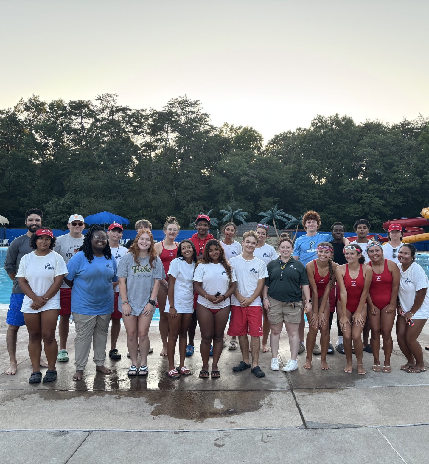 Group of diverse lifeguards standing outdoors at a poolside.