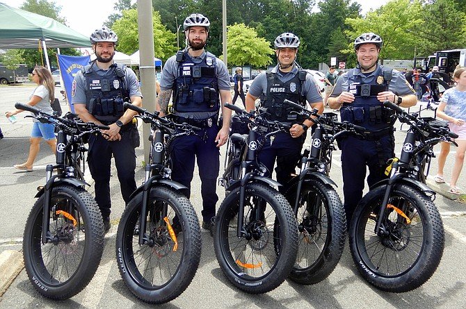 Four police officers standing with bicycles at an outdoor event.