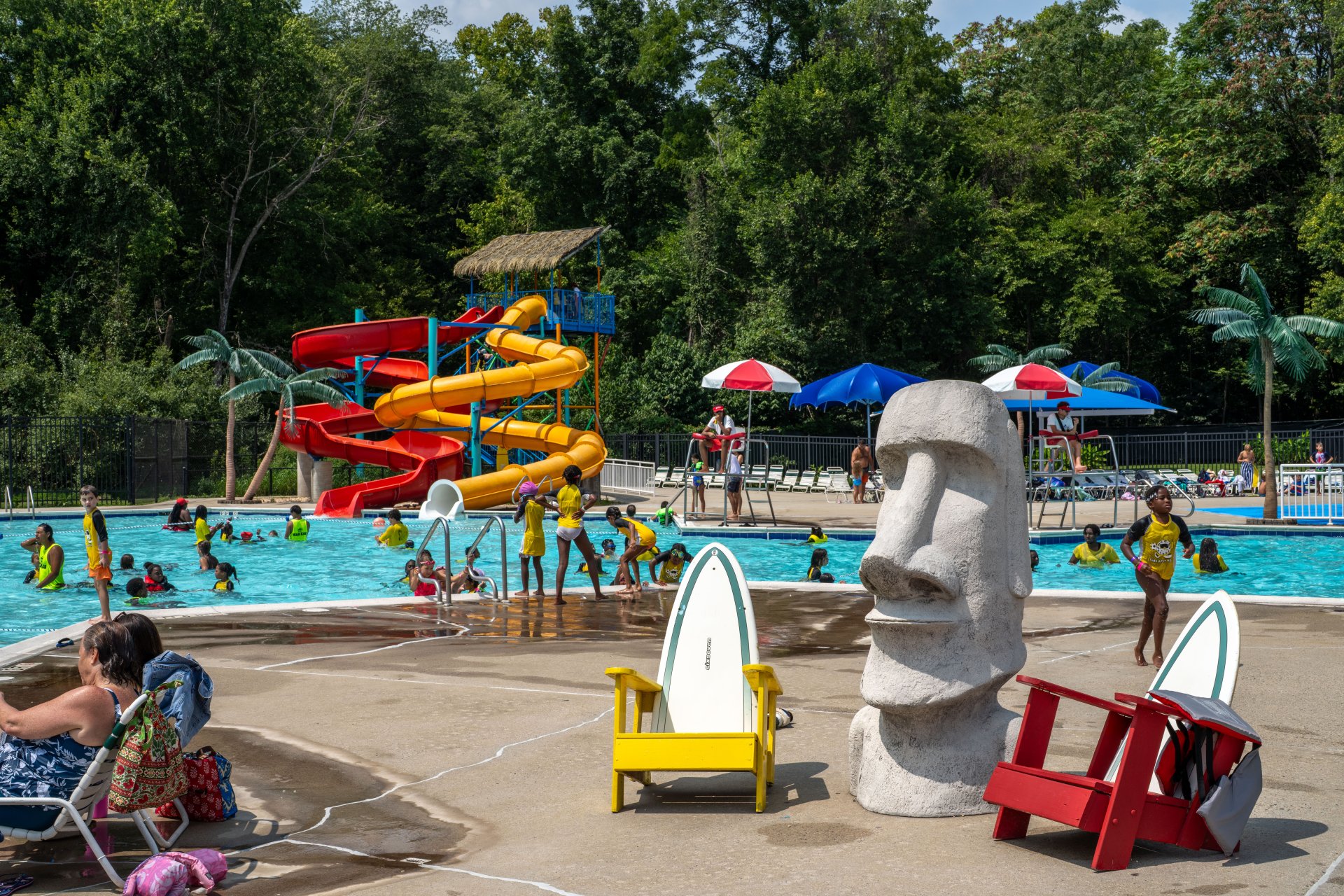 Outdoor pool with slides, people swimming, and colorful umbrellas.